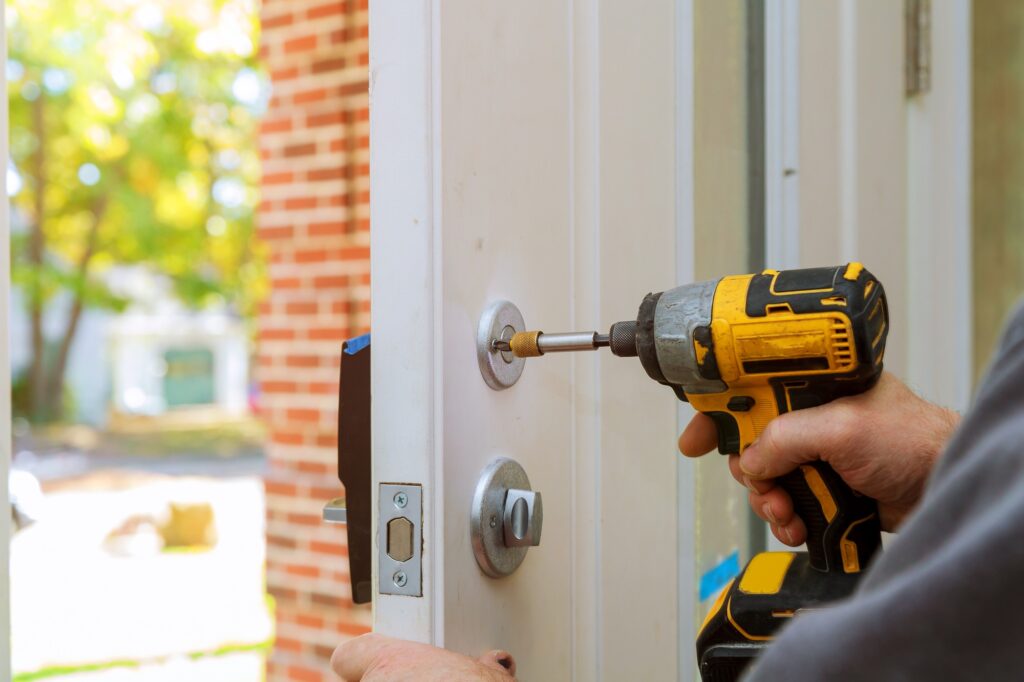 man repairing the doorknob. closeup of worker's hands installing new door locker
